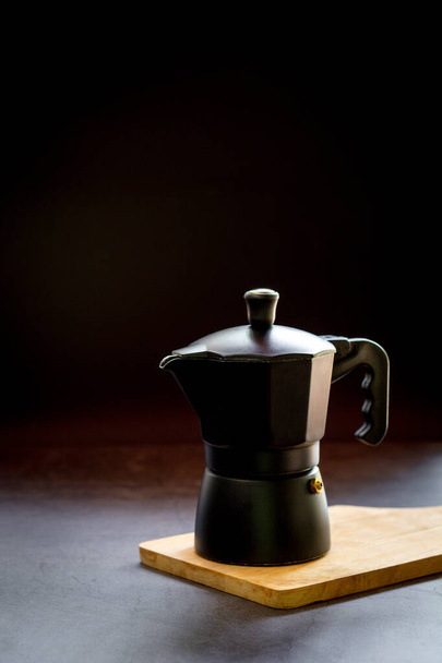 木製のまな板と暗いテーブルの上にエスプレッソやブラックコーヒーやモカ鍋。コーヒーコンセプトの利点.  - 写真・画像