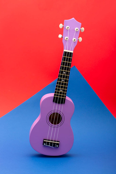 4弦ウクレレギターの赤と青の背景 - 写真・画像