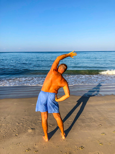 a man goes in for sports, does exercises on the seashore - Foto, Imagem