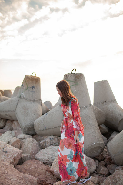 Beautiful woman in a long red dress near breakwater, a walk by the sea - Foto, Bild