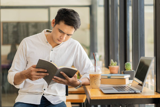 Молодые азиатские мужчины, будущие студенты для самообучения или личных идей обучения. Онлайн-студенты в кафе с книгами и ноутбуками. - Фото, изображение