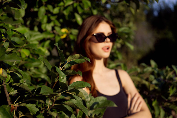 pretty woman in sunglasses in summer outdoors green leaves - Photo, Image