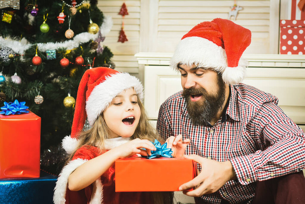 Happy Father and daughter child with present gift in santa hat at Christmas tree. Winter family holiday and happy New year - Фото, зображення
