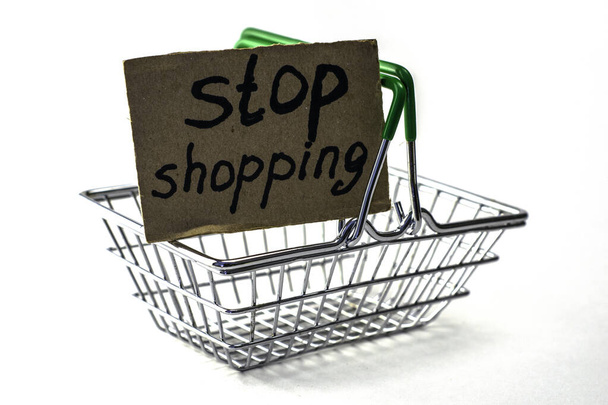 koncept odmítnutí koupit rozumnou spotřebu je nákupní košík s nápisem stop nakupování na bílém pozadí. Kvalitní fotografie - Fotografie, Obrázek