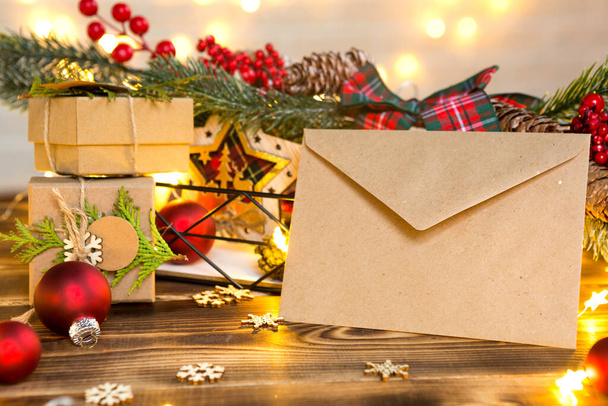 Envelope from kraft paper with congratulations and invitation for Christmas and new year in festive decor, fairy lights. Letter for Santa Claus. Mock up, natural decor, hand made. Copy space - Φωτογραφία, εικόνα