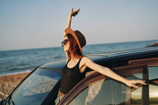 woman on the beach is with a car wearing sunglasses travel - Photo, Image