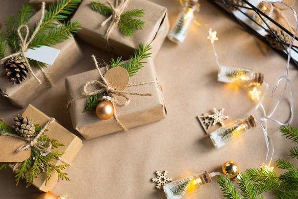 Pack a gift for Christmas and new year in eco-friendly materials: kraft paper, live fir branches, cones, twine. Tags with mock up, natural decor, hand made, DIY. Festive mood. Flatly, background - Photo, image