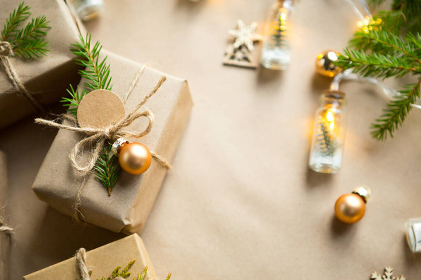 Pack a gift for Christmas and new year in eco-friendly materials: kraft paper, live fir branches, cones, twine. Tags with mock up, natural decor, hand made, DIY. Festive mood. Flatly, background - 写真・画像