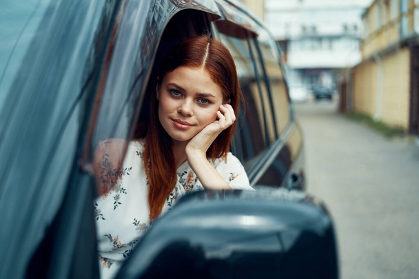 cheerful woman driving a car looks out of the window - Foto, imagen