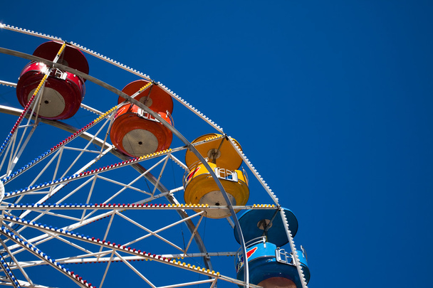 Multi-colored ferris wheel against a blue sky - Фото, изображение