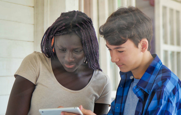 Chica africana hablando en la escuela con compañero de escuela caucásico. - Foto, imagen