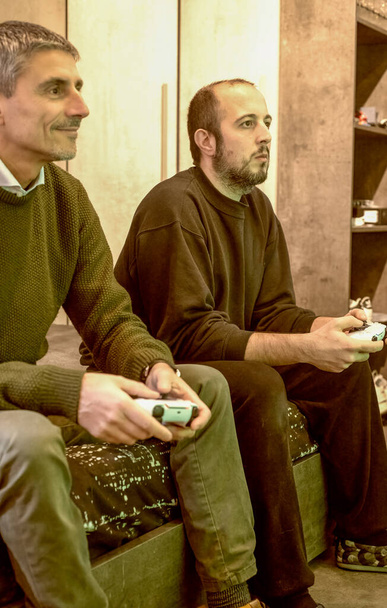 2人の男がゲーム機でゲームをプレイ. - 写真・画像