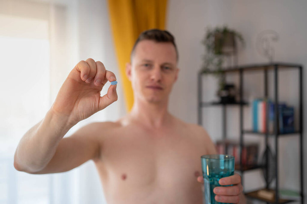 Ein junger Mann nimmt ein Präparat in einer Pille. HIV-Präventionskonzept. AIDS-Präventionskonzept. HIV AIDS - Foto, Bild