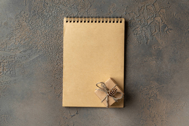 Christmas or New Year holiday background with an open notebook and gift box. The concept of a checklist of gifts or a letter to Santa. Top view with a copyspace - Zdjęcie, obraz