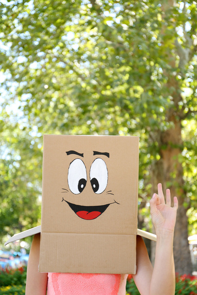 Woman with cardboard box on her head with happy face, outdoors - Foto, Imagen