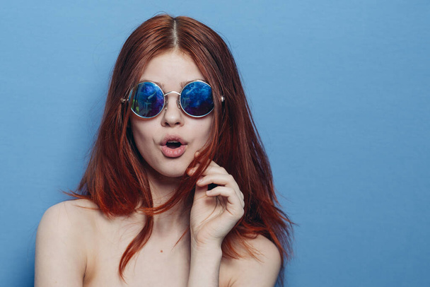 perky red-haired woman in blue glasses bare shoulders posing - Фото, изображение