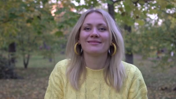 Vrouw gooit gele herfstbladeren in het park, slow motion. Gouden herfst, portret van een gelukkige vrouw - Video