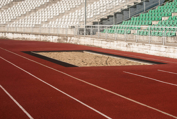 Atletismo pista de superfície vermelha e armadilha de areia para salto longo e salto triplo - Foto, Imagem