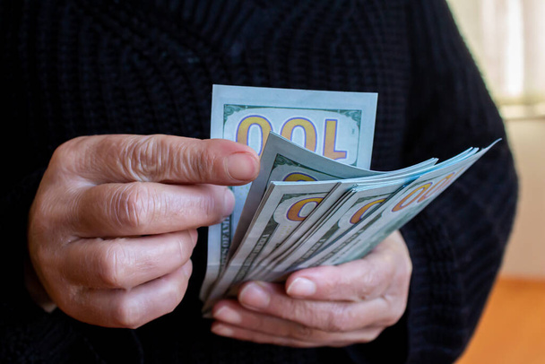 Zbliżenie kobieta trzyma i liczy banknoty dolarowe, banknoty pieniężne w ręku. - Zdjęcie, obraz