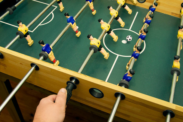 Hand holds the control stick of toy soccer players while playing table football - Fotografie, Obrázek