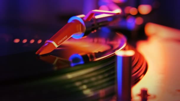 Pracujący gramofon z obrotową płytą winylową. Neonowe niebiesko-czerwone oświetlenie wokół - Materiał filmowy, wideo