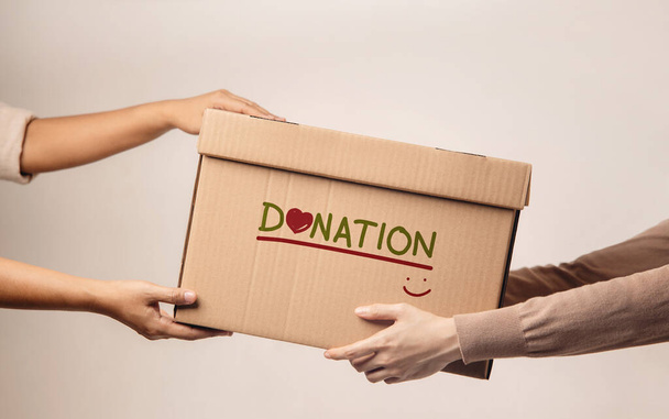 Spendenkonzept. Der Freiwillige, der dem Empfänger eine Spendenbox übergibt. Gegen das Walll - Foto, Bild