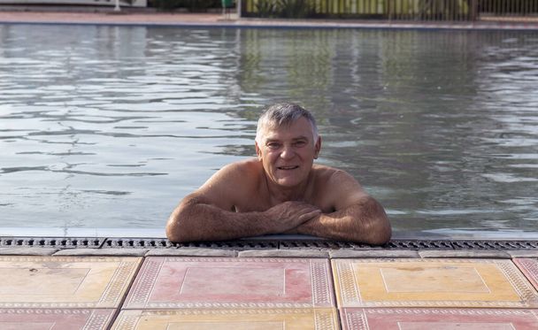 Portret uśmiechniętego dojrzałego mężczyzny w zewnętrznym basenie termalnym. Koncepcja zdrowia fizycznego. - Zdjęcie, obraz