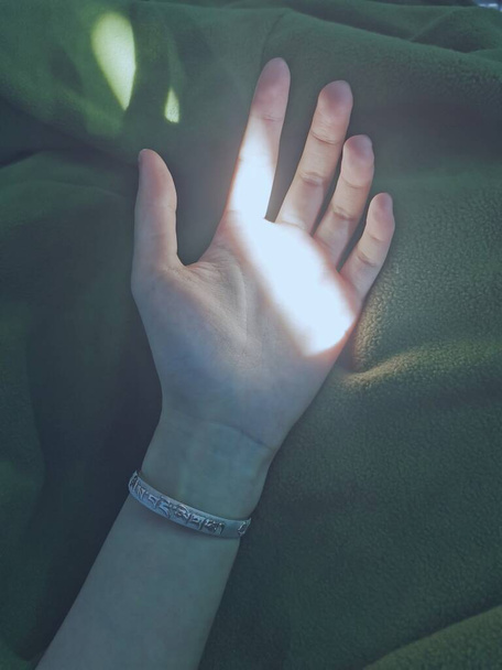 close-up van een vrouw de hand met een zwart handvat op een groene achtergrond - Foto, afbeelding