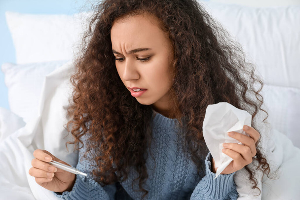 Afro-Amerikaanse vrouw ziek met griep in bed thuis - Foto, afbeelding
