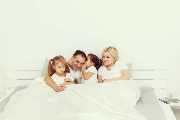 子供と両親はベッドで朝休みです。彼らは楽しむ、抱擁。双子だ。木の娘. - 写真・画像