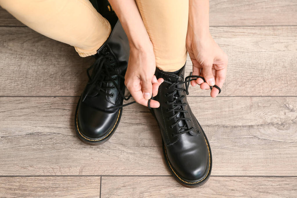 Woman in black boots tying shoe laces at home, closeup - Fotoğraf, Görsel