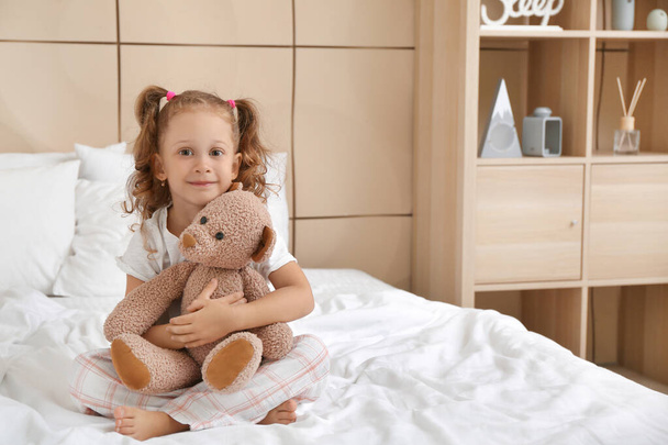 Αξιολάτρευτο κοριτσάκι με αρκουδάκι στην κρεβατοκάμαρα. - Φωτογραφία, εικόνα