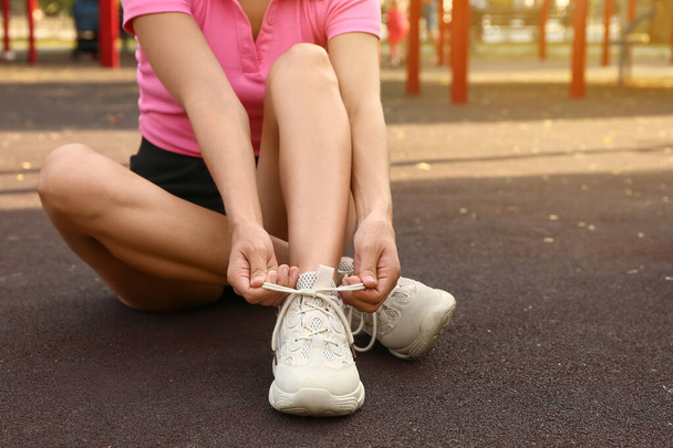 Donna in scarpe da ginnastica bianche allacciatura lacci sul terreno sportivo - Foto, immagini