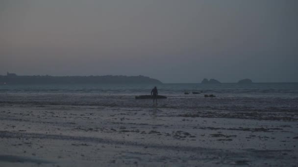 Мандрівник ходить по піску пляжу під час низького припливу Атлантичного океану на півночі Франції. Чоловік на заході сонця ходить по морському узбережжю і пливе в Бретані. Низька вода або рефлюенс - Кадри, відео