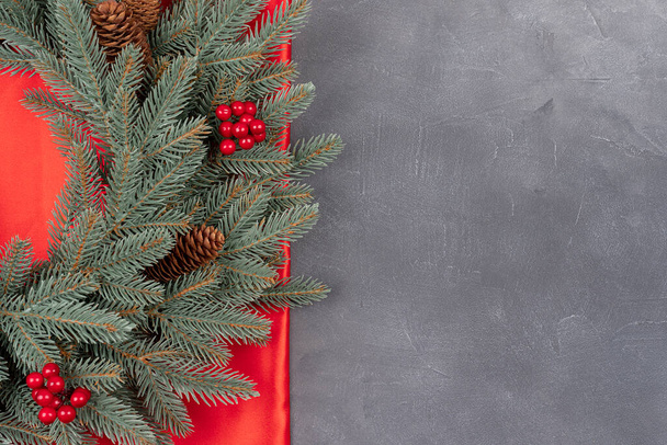 灰色の具体的な背景と赤い絹の背景にクリスマスツリーのクリスマスの境界線。招待テキスト、トップビューのコピースペース付きのトップビューとフラットレイアウト - 写真・画像