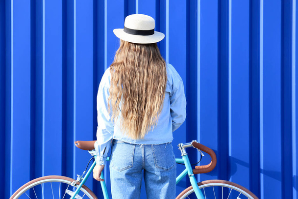 Hübsches Teenager-Mädchen mit Fahrrad in der Nähe von blauem Zaun - Foto, Bild