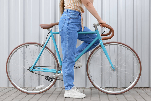 Красивая девочка-подросток с велосипедом возле синего забора - Фото, изображение