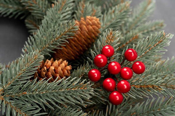 Schöner roter Weihnachtskranz. Eingang zum Haus. Weihnachtsstimmung. Nahaufnahme von oben, Neujahr dekorativ. Tannenzapfen mit Beeren - Foto, Bild