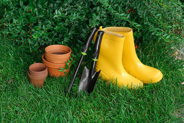 Садовые инструменты и сапоги на зеленой траве на открытом воздухе - Фото, изображение