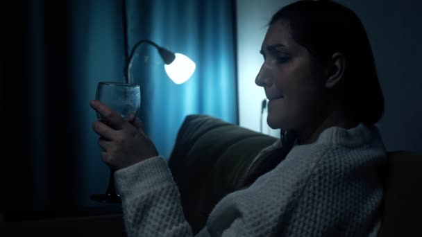 Deprese žena pije alkohol v temnotě obývacího pokoje - Záběry, video