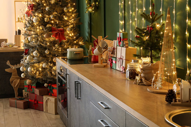 Πάγκοι κουζίνας με χριστουγεννιάτικα δώρα και διακόσμηση κοντά σε πράσινο τοίχο - Φωτογραφία, εικόνα