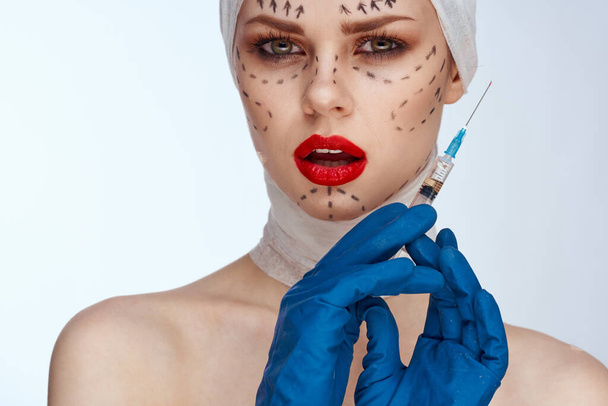 woman in blue gloves syringe in hands contour on the face lifting light background - Фото, изображение