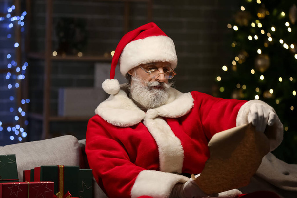 Santa Claus reading wish list at home on Christmas eve - Foto, afbeelding