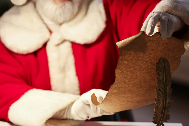 Weihnachtsmann liest Wunschzettel zu Hause am Heiligen Abend - Foto, Bild