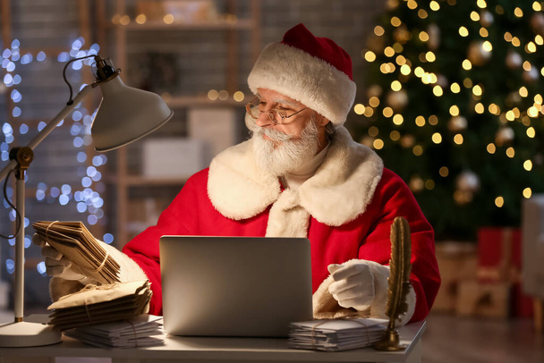 Santa Claus s laptopem a dopisy doma na Štědrý den - Fotografie, Obrázek