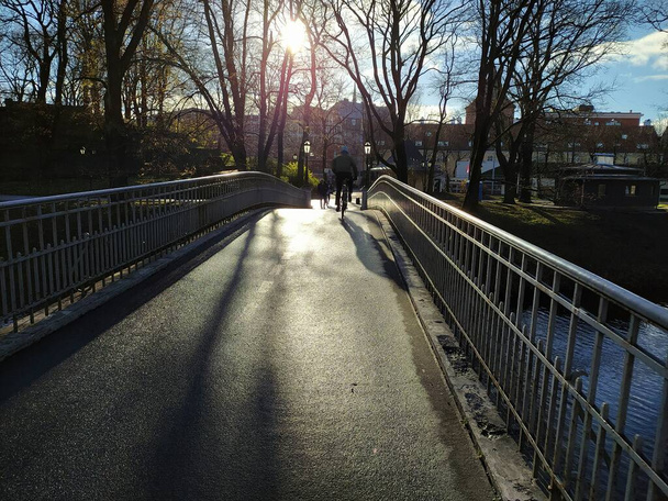 Lettország, Riga, 2021. november 12. Egy híd a rigai csatornán át napközben, háttérvilágítással.. - Fotó, kép