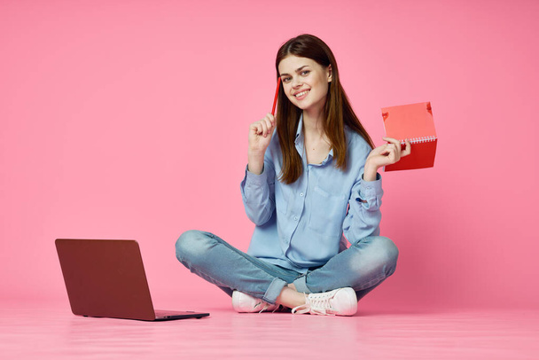 woman sitting on floor with laptop shopping entertainment pink background - Fotoğraf, Görsel
