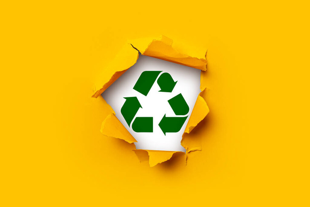 Cartão de papel rasgado amarelo brilhante dentro de um sinal de buraco reciclagem de resíduos de papel e sucata de metal  - Foto, Imagem