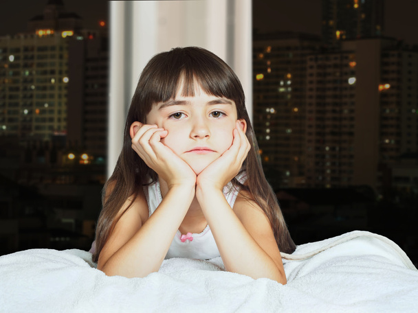 Portrait of caucasian sad girl child kid on background window at night - Valokuva, kuva