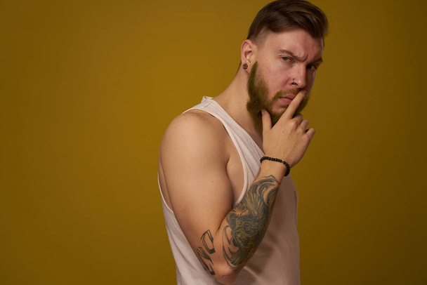 bearded man in white t-shirt with tattoos on his arms posing serious look - Foto, Bild